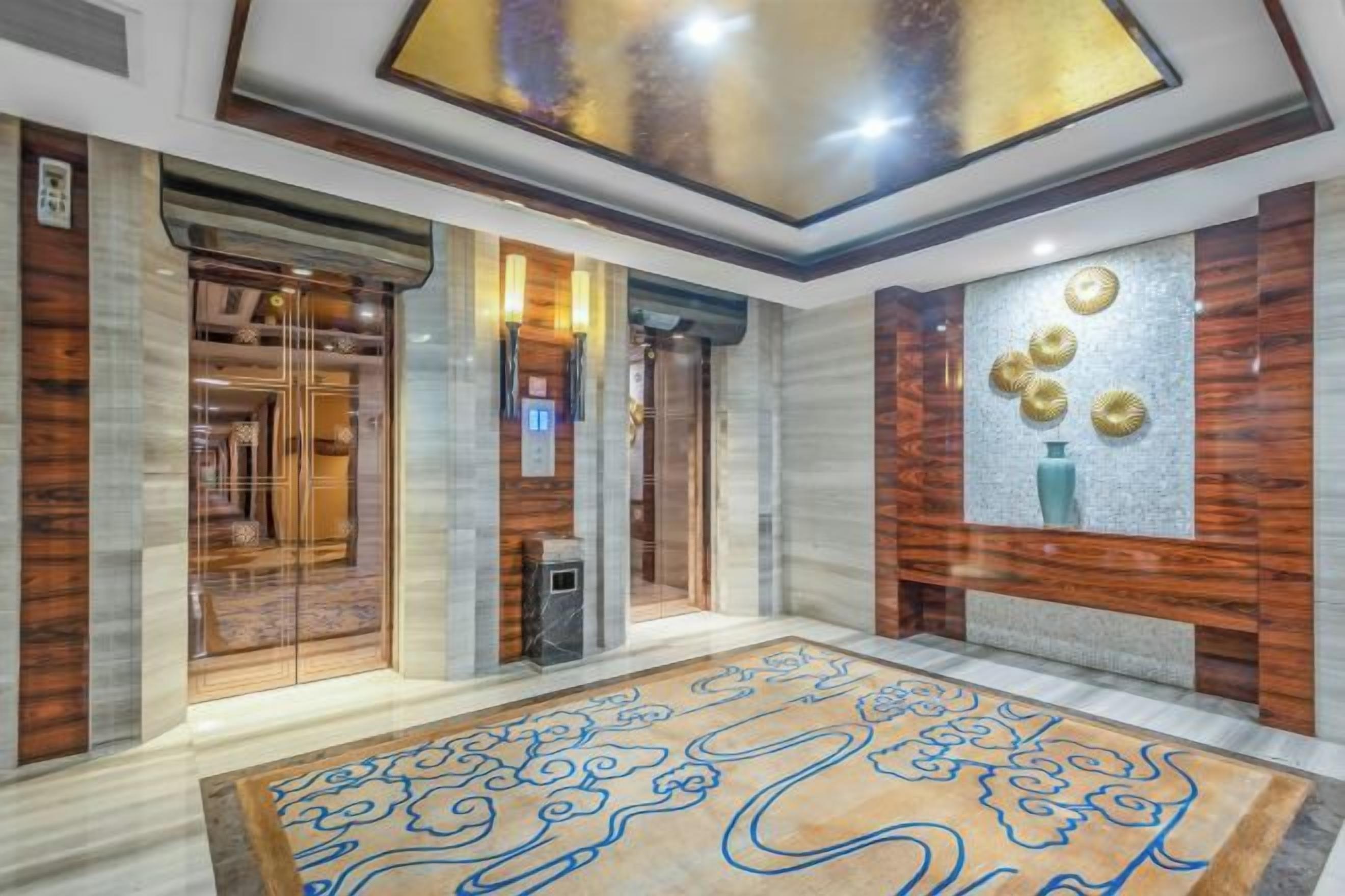 A hotel lobby with a marble floor, a reception desk, and a wall-mounted decorative piece.