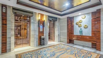 A hotel lobby with a marble floor, a reception desk, and a wall-mounted decorative piece.