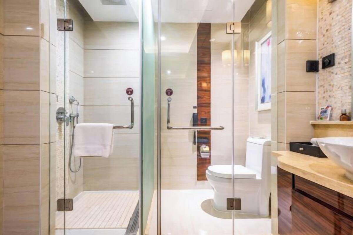 A modern bathroom with a glass shower enclosure, a white toilet, and a wooden accent wall.