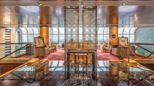 A spacious lobby with a marble floor, a central seating area, and a decorative wall with intricate patterns. - Prestton Hotel (Jinan)