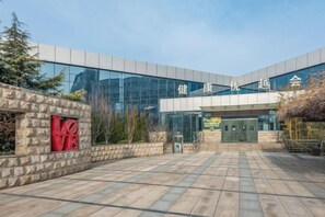 A modern building with a glass facade and a stone wall with a red 'LOVE' sign. - Prestton Hotel (Jinan)