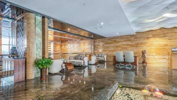 Um lobby moderno com balcão de recepção de mármore, área de estar e parede decorativa.