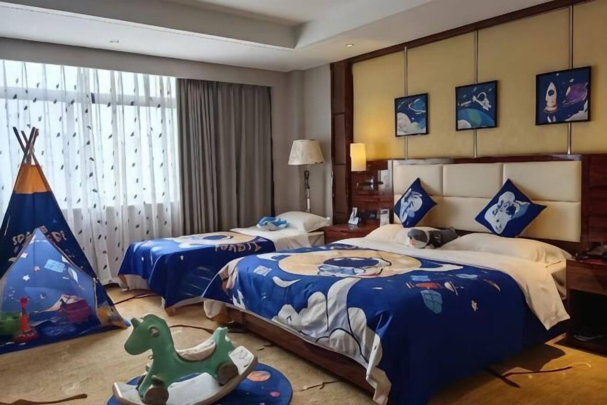 A hotel room with two beds, a window with curtains, a lamp, and a teepee decoration.