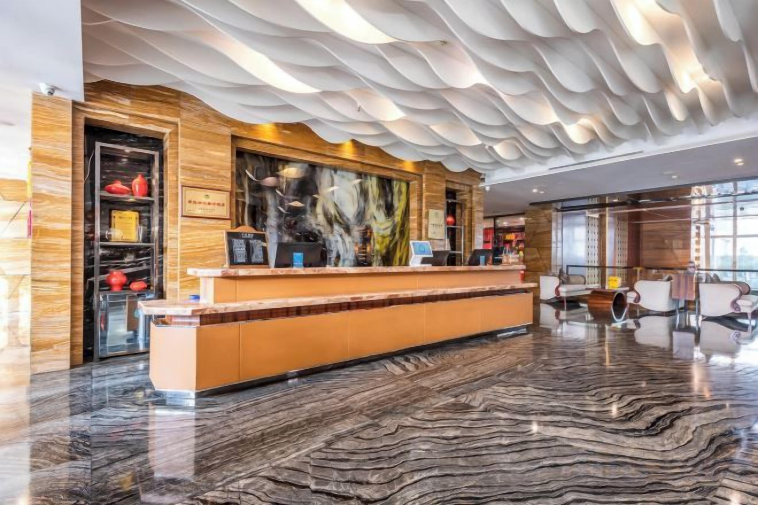 A hotel lobby with a reception desk, seating area, and a large window.