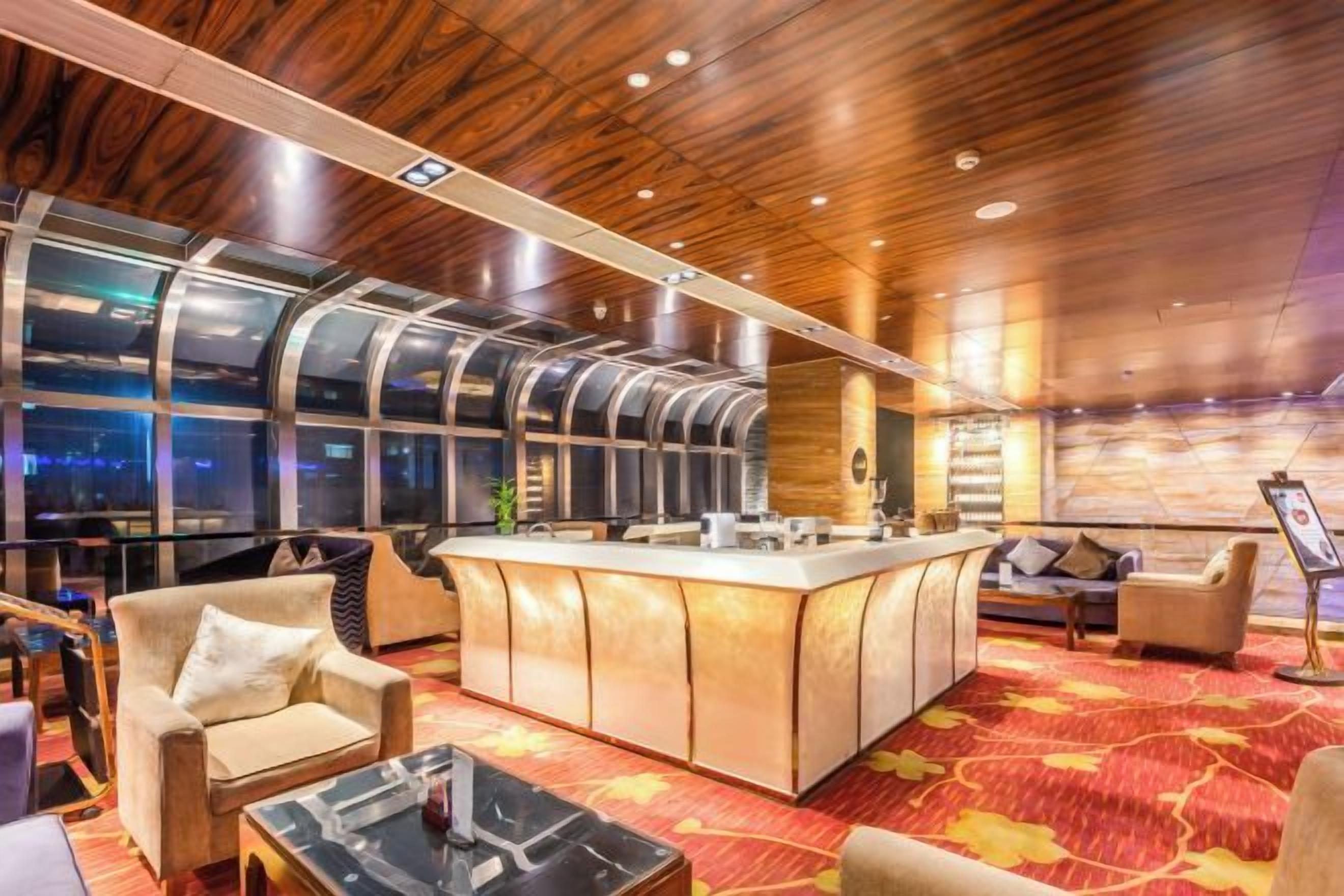 A modern hotel lobby with a bar area, seating, and large windows.