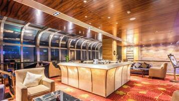 A modern hotel lobby with a bar area, seating, and large windows.
