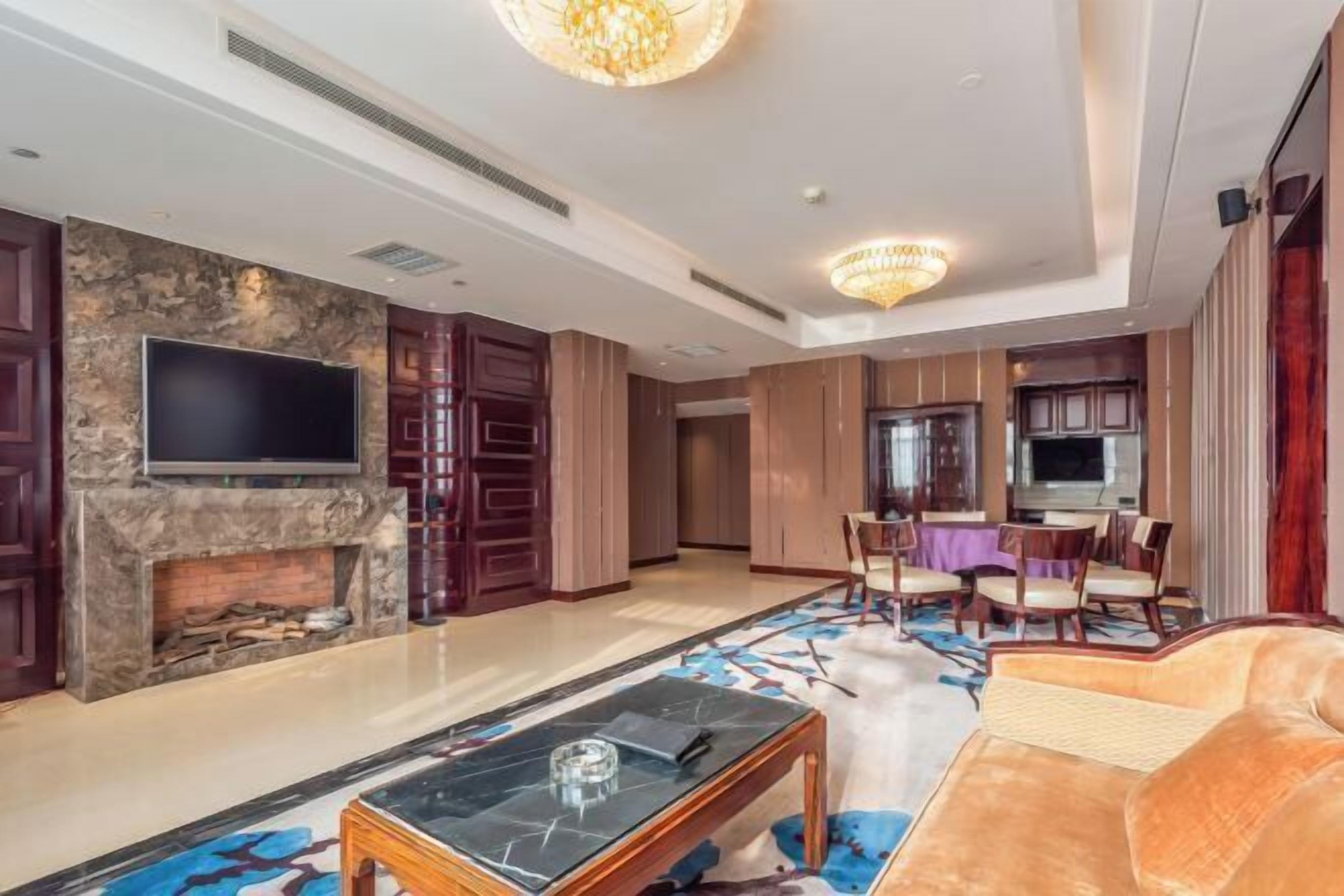 A spacious living area with a fireplace, a flat-screen TV, a dining table with chairs, and a plush sofa.