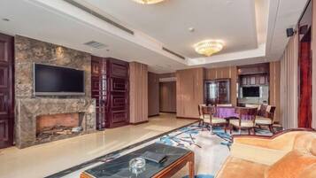 A spacious living area with a fireplace, a flat-screen TV, a dining table with chairs, and a plush sofa.