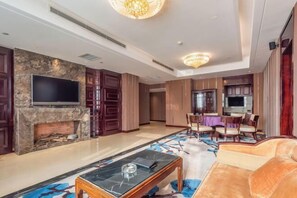 A spacious living area with a fireplace, a flat-screen TV, a dining table with chairs, and a plush sofa. - Prestton Hotel (Jinan)