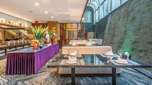 A modern restaurant with a glass dining area, a buffet with various food items, and a seating area with tables set for dining. - Prestton Hotel (Jinan)