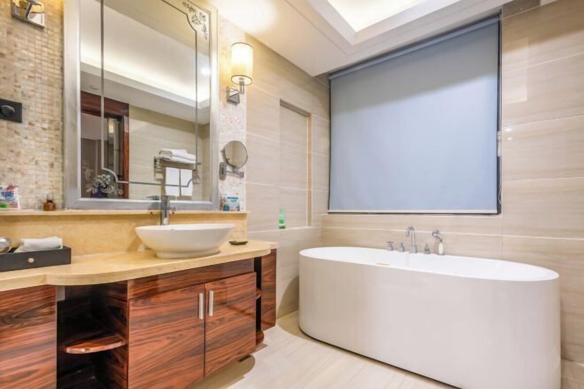 A modern bathroom with a freestanding bathtub, a large mirror, and a vanity with a vessel sink.