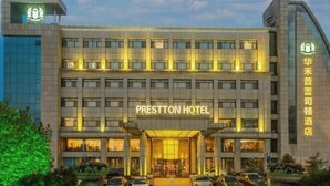 A multi-story hotel with a prominent entrance, illuminated signage, and a parking area in front. - Prestton Hotel (Jinan)