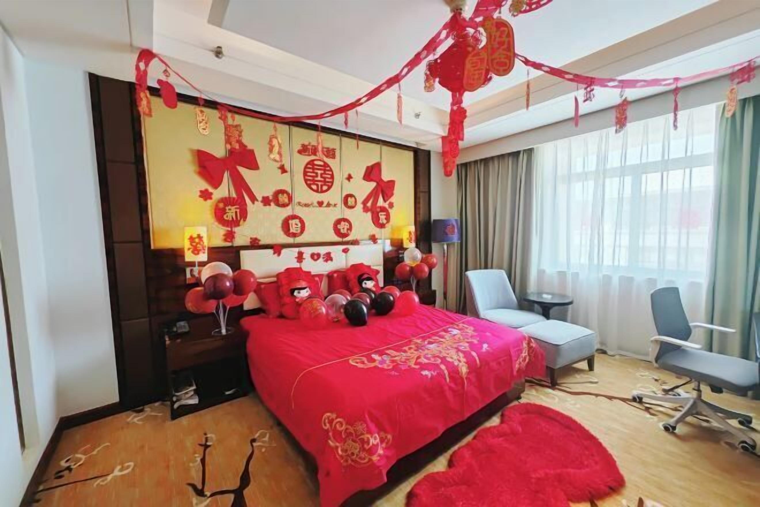 A hotel room with a large bed, a desk, a chair, and a window with curtains.