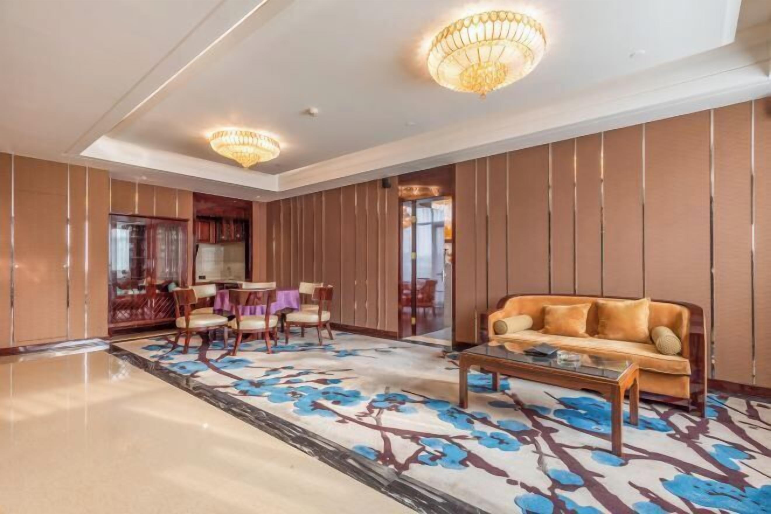 A spacious lobby with a large sofa, a coffee table, and a dining area with chairs and a table.