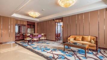 A spacious lobby with a large sofa, a coffee table, and a dining area with chairs and a table.