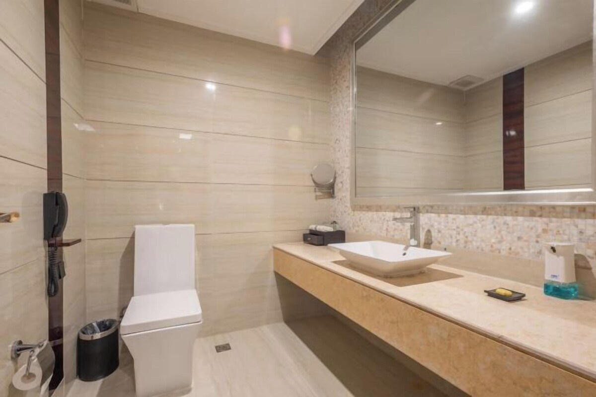 A modern bathroom with a white toilet, a large sink, and a mirror.