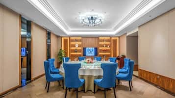 A conference room with a round table, blue chairs, and a chandelier.