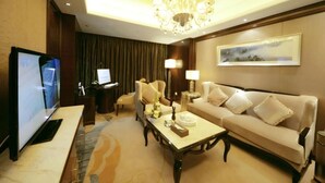Un salón bien iluminado con televisión, sofá, mesa de centro y candelabro.