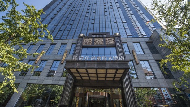 Un edificio moderno con fachada de vidrio y una entrada tradicional con un arco decorativo.