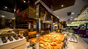 Mostrador de panadería con diversos productos horneados y una zona de estar con mesas y sillas.