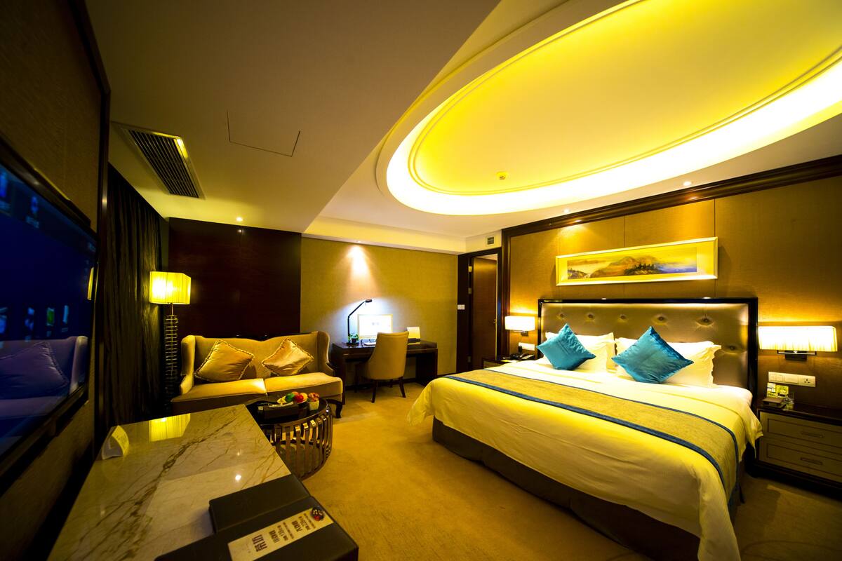Une chambre d’hôtel avec un grand lit, un bureau, une chaise, une télévision et une salle de bain.