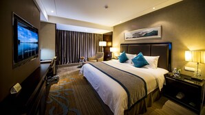 Habitación de hotel con una cama grande, un televisor, un escritorio y una silla.