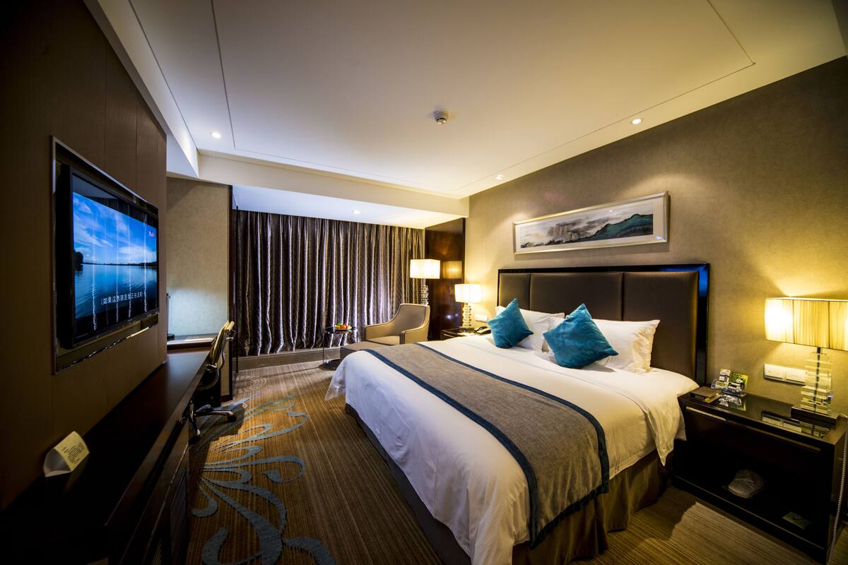 Une chambre d’hôtel avec un grand lit, une télévision, un bureau et une chaise.