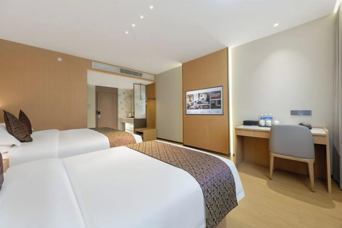 A hotel room with two beds, a desk, and a chair.