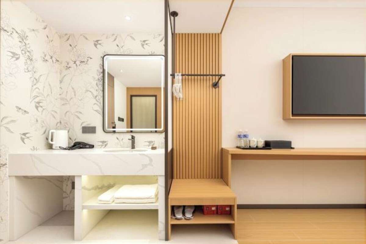 Een badkamer met een wastafel, spiegel, handdoekrek en douche.