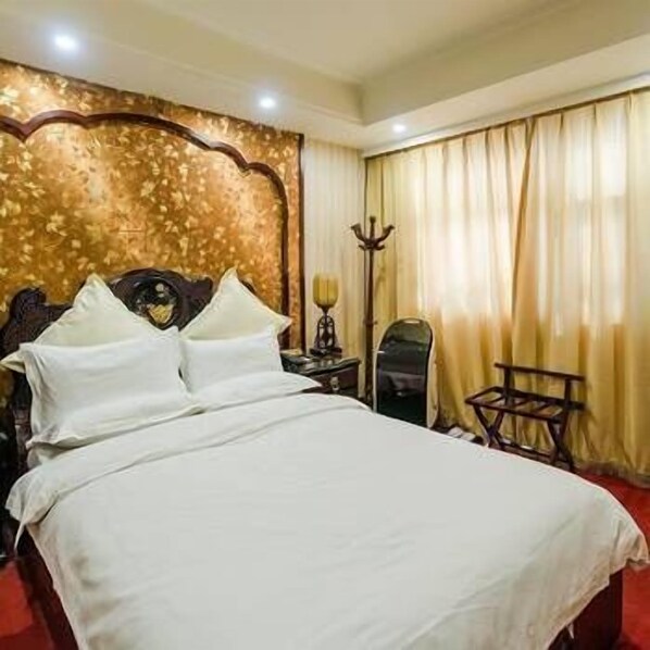 A hotel room with a large bed, a wooden headboard, and a red carpet. - Huanghe Jingdu Grand Hotel (Beijing)