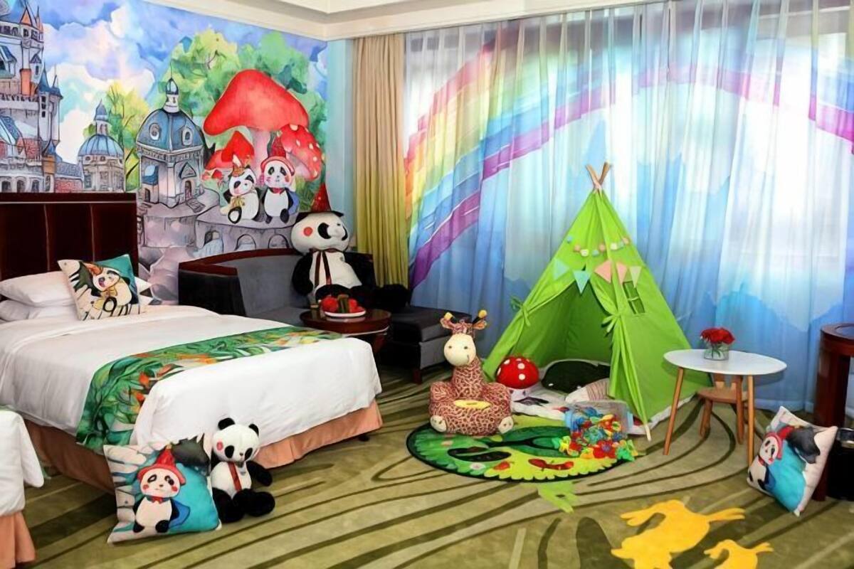 A children's room with a bed, a green tent, plush toys, and a mural.