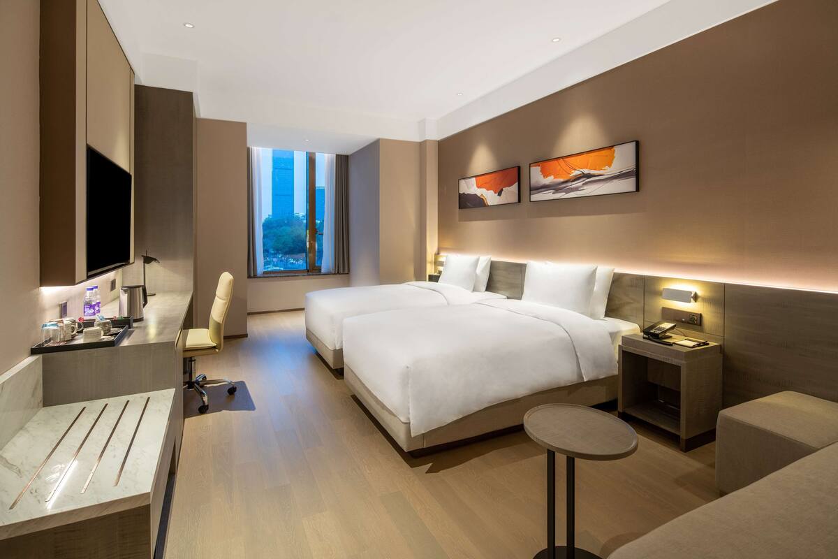 A modern hotel room with a large bed, bedside tables, a desk, and a TV.