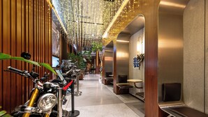 Un pasillo moderno de hotel con una fila de motocicletas, zonas de estar y un techo decorativo.