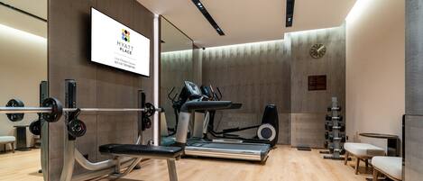 Un gimnasio moderno con equipo de ejercicio, un reloj y un espejo.