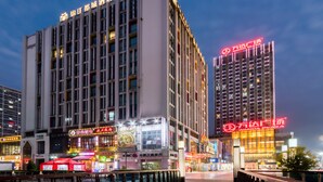 A hotel with multiple floors, large windows, and illuminated signage. - Metropolo Shaoxing Keqiao Wanda Square (Shaoxing)