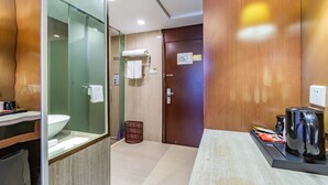 A modern bathroom with a glass shower enclosure, a sink, and a toilet. There is a wooden door with a towel rack and a coffee machine on the counter. - Metropolo Shaoxing Keqiao Wanda Square (Shaoxing)