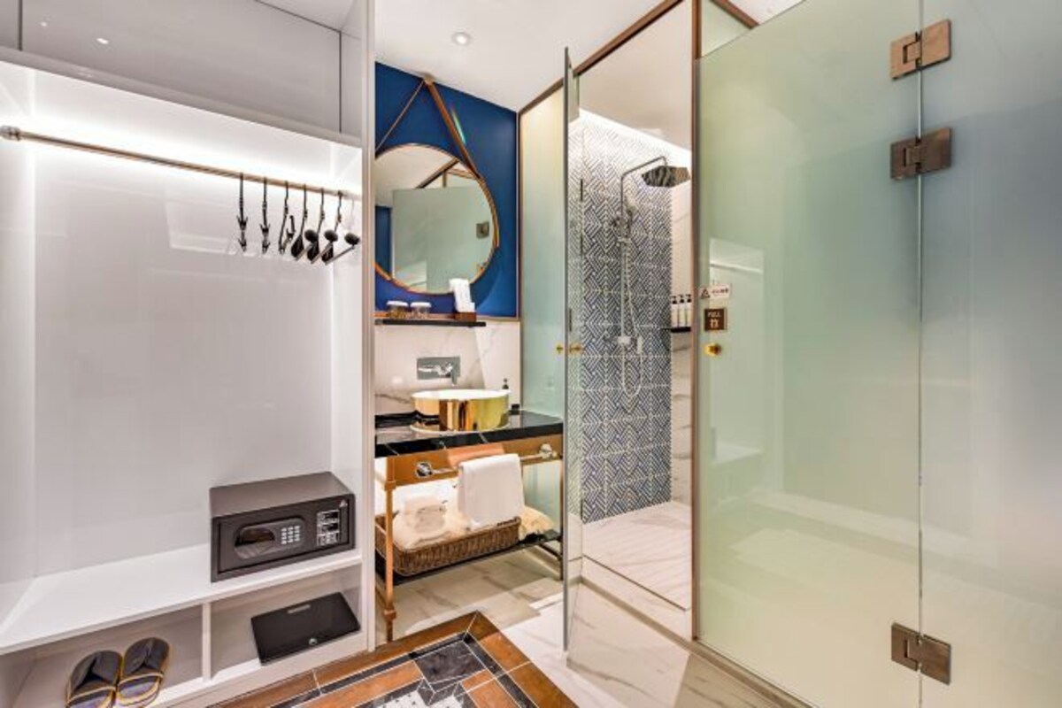Un baño moderno con tocador, ducha con puerta de vidrio y microondas empotrado.