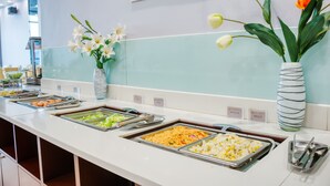 A buffet area with various food options and a vase with flowers. - Metropolo Shaoxing Keqiao Wanda Square (Shaoxing)