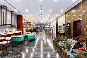 En moderne hotellobby med marmorgulv, siddeområder og en receptionsdisk.