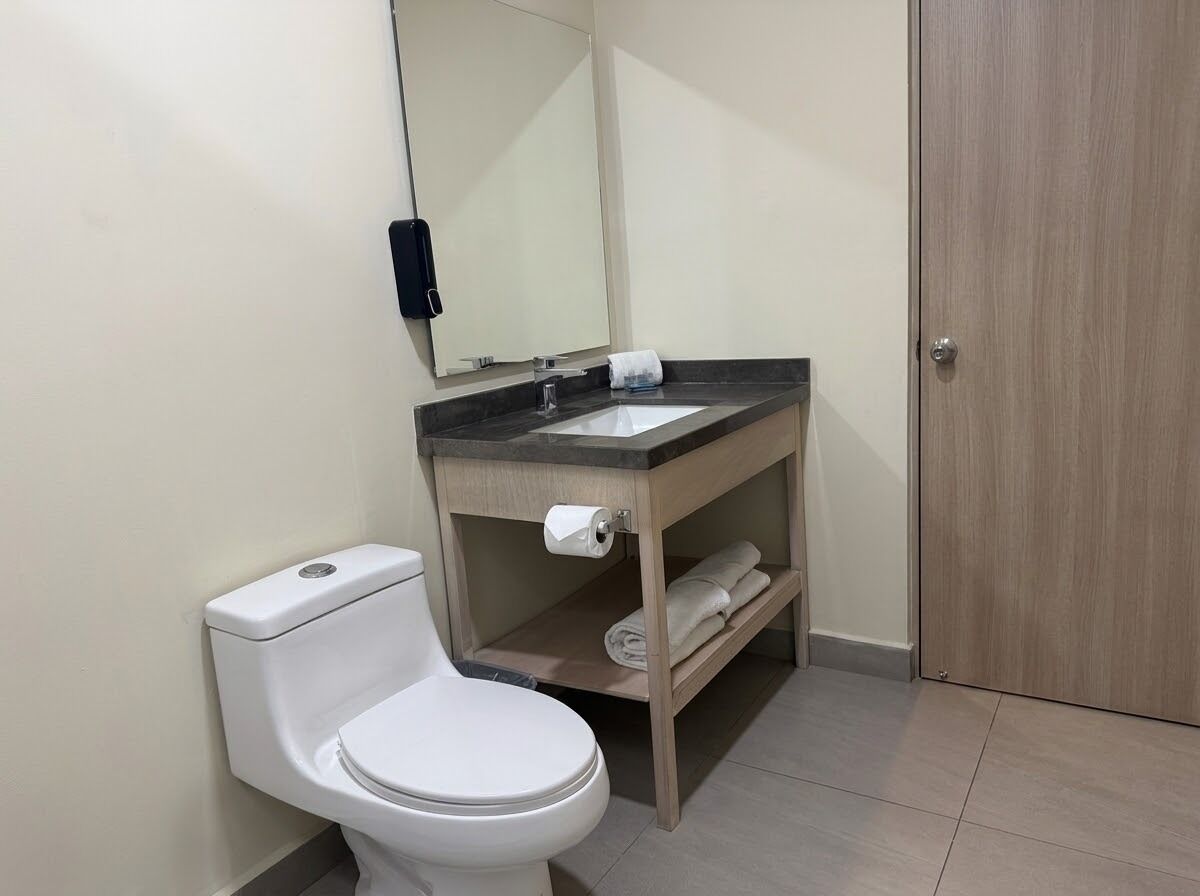 A bathroom with a toilet, sink, and mirror.