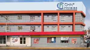 Un hotel de varios pisos con un llamativo letrero de CNH Hotels, que presenta un diseño arquitectónico moderno con fachada roja y gris.