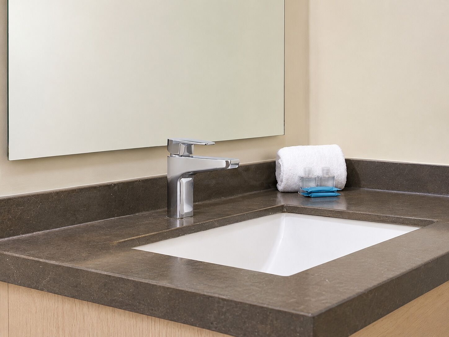 Un baño con lavamanos blanco, un espejo y una toalla.