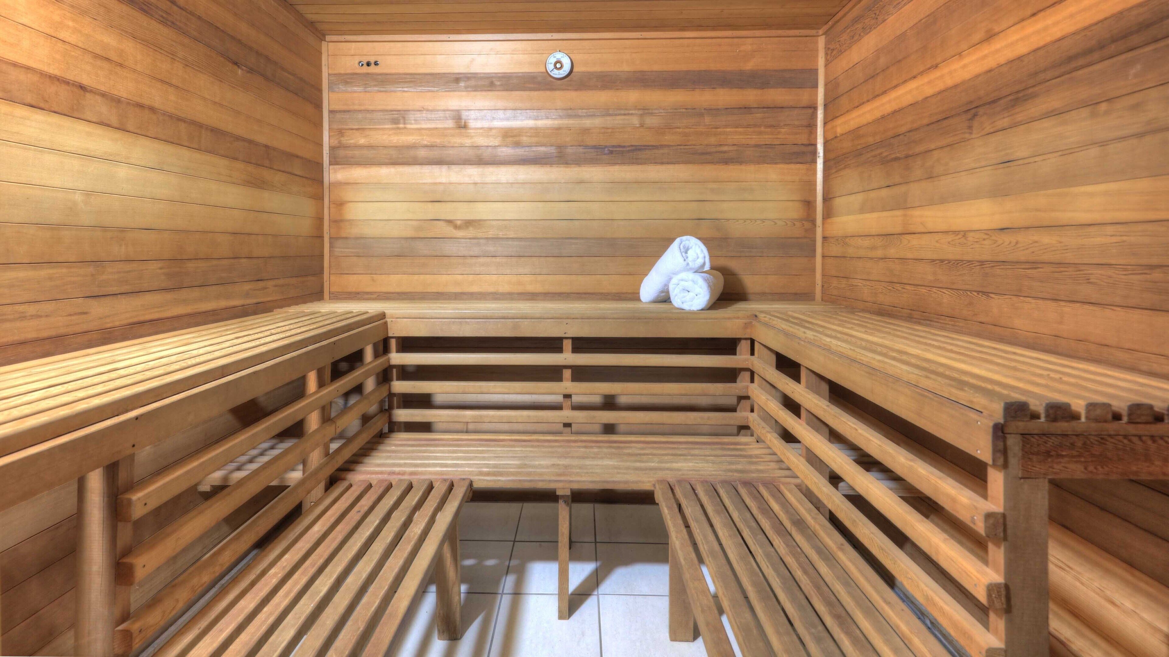 Una sauna con bancos de madera y un banco con toallas.