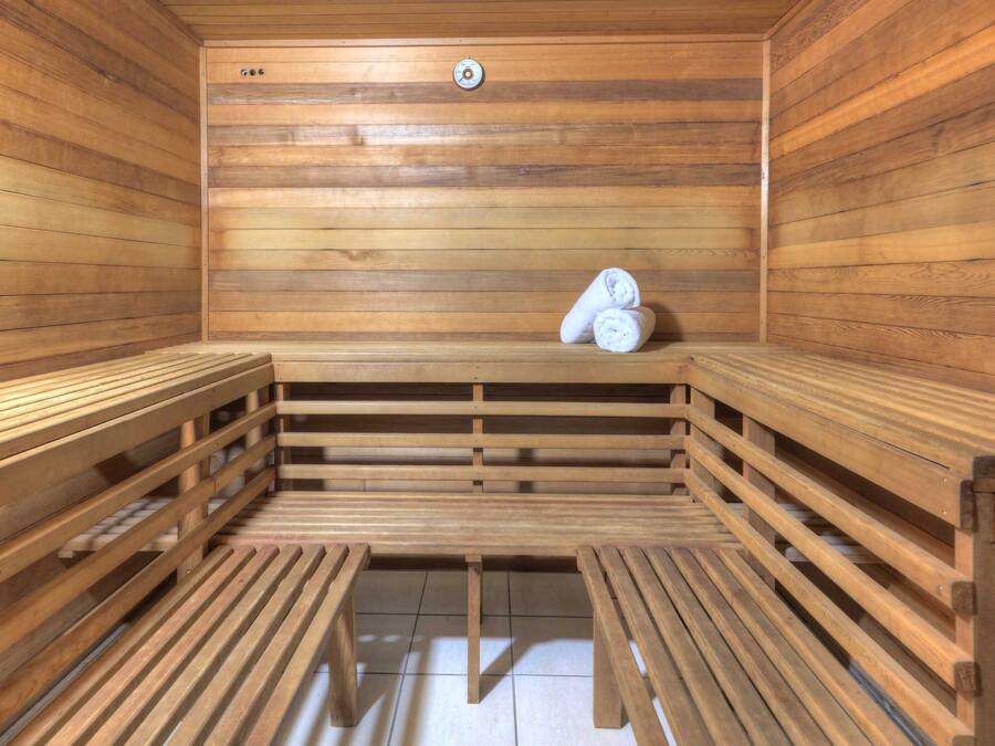 A sauna with wooden benches and a bench with towels.