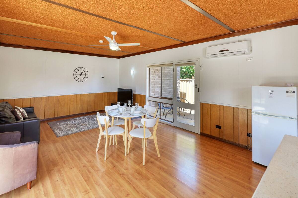 Un espacio habitable compacto con comedor, sofá, televisor y refrigerador.