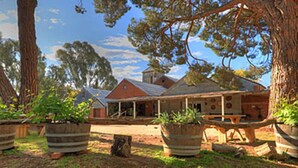 A rustic building with a covered porch and large potted plants in front. - Motel Meneres (Corowa)