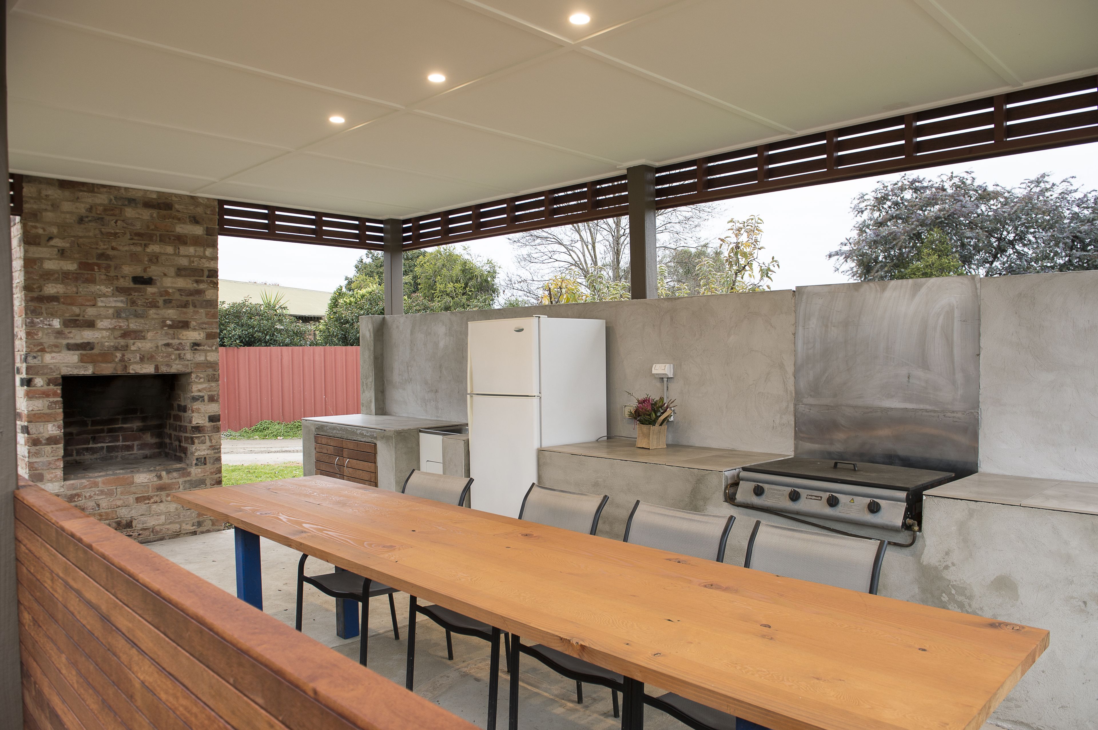 Una cocina exterior con horno de ladrillo, estufa a gas y refrigerador.