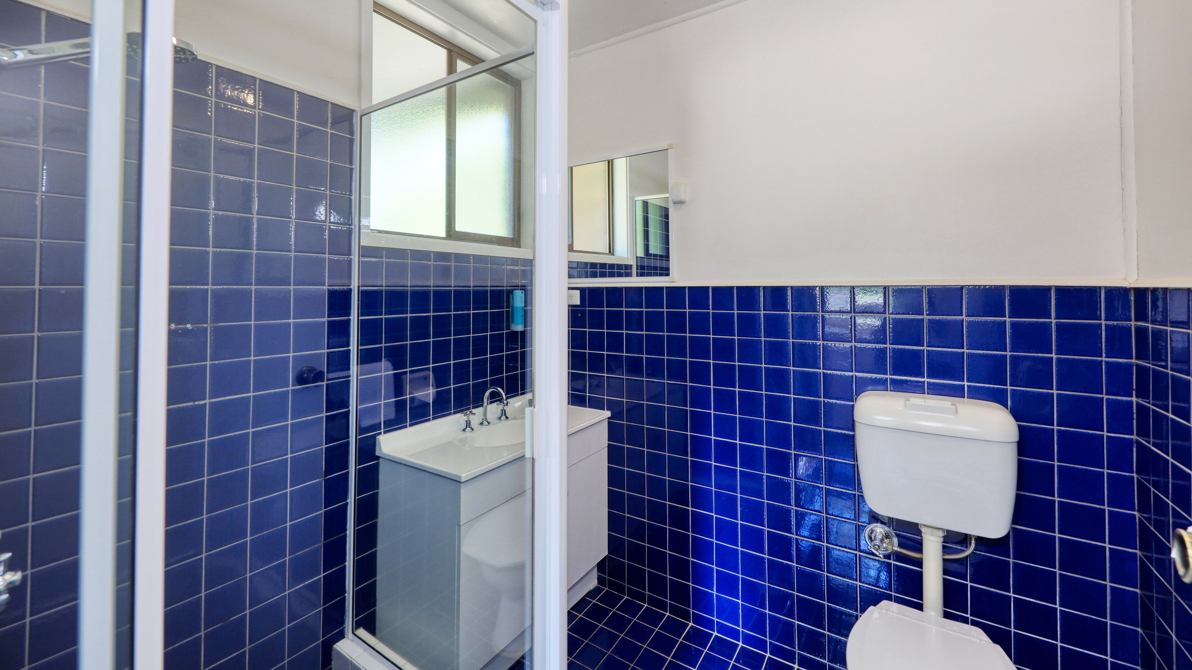 Un baño con azulejos azules, un lavabo blanco y un inodoro.
