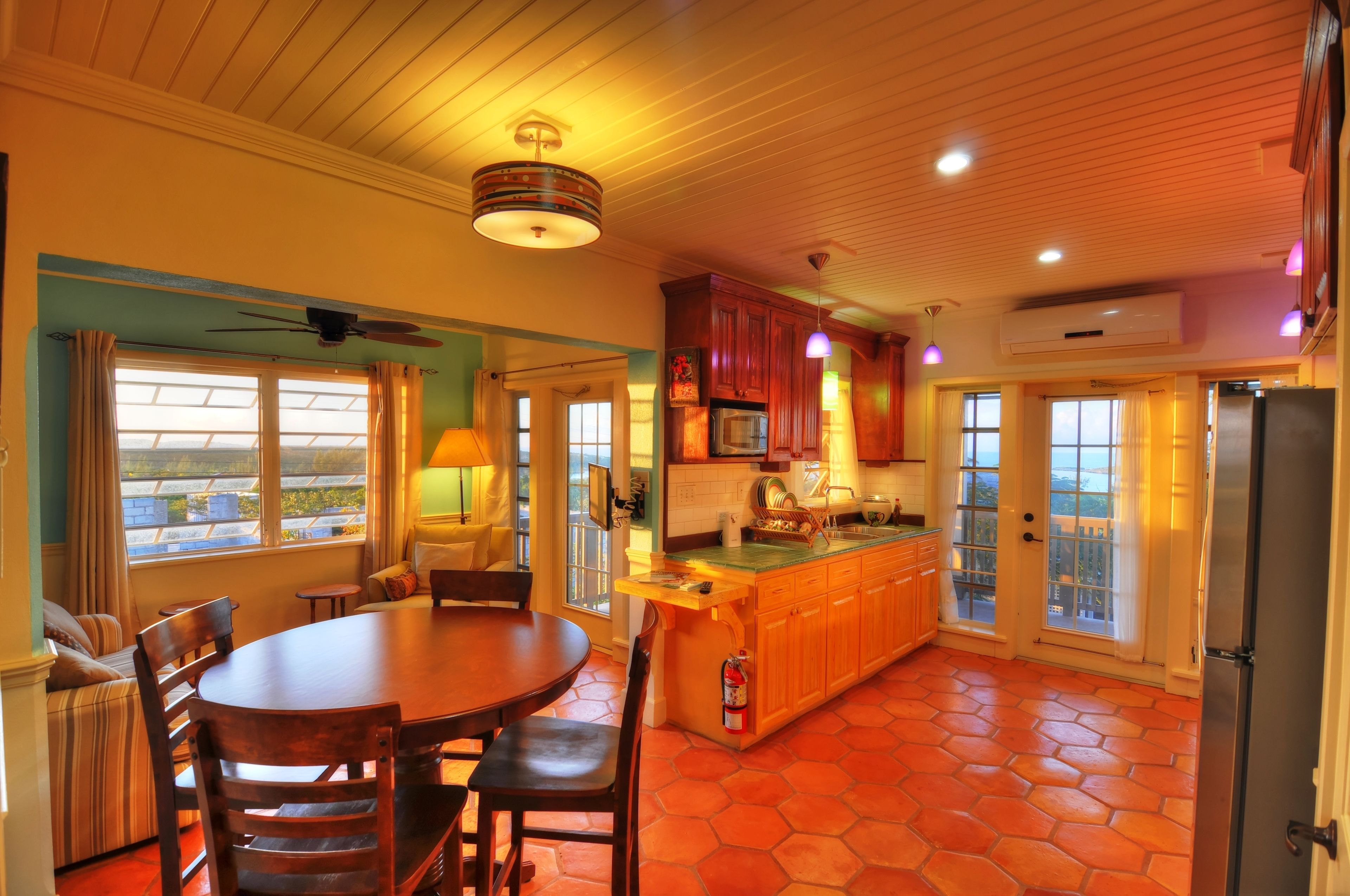 A kitchen with a dining area, wooden cabinets, a refrigerator, and a ceiling fan.