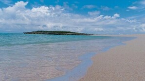 A beach with clear turquoise water, a sandy shore, and a small island in the distance. - Villa Allamanda (Governor's Harbour)